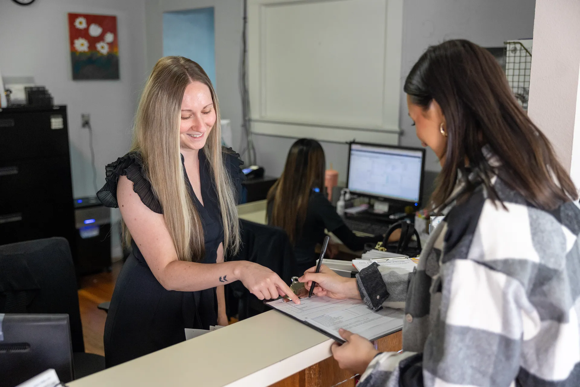 employee at desk pointing at document in front of patient