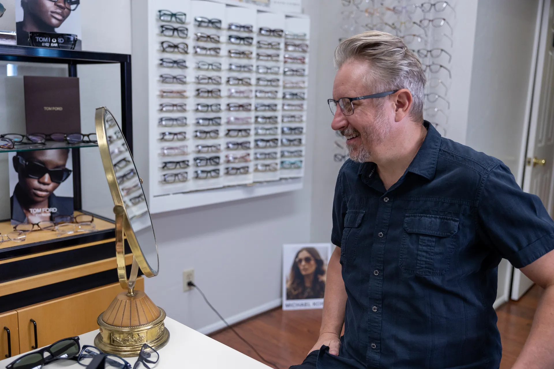 a man wearing glasses looking into mirror
